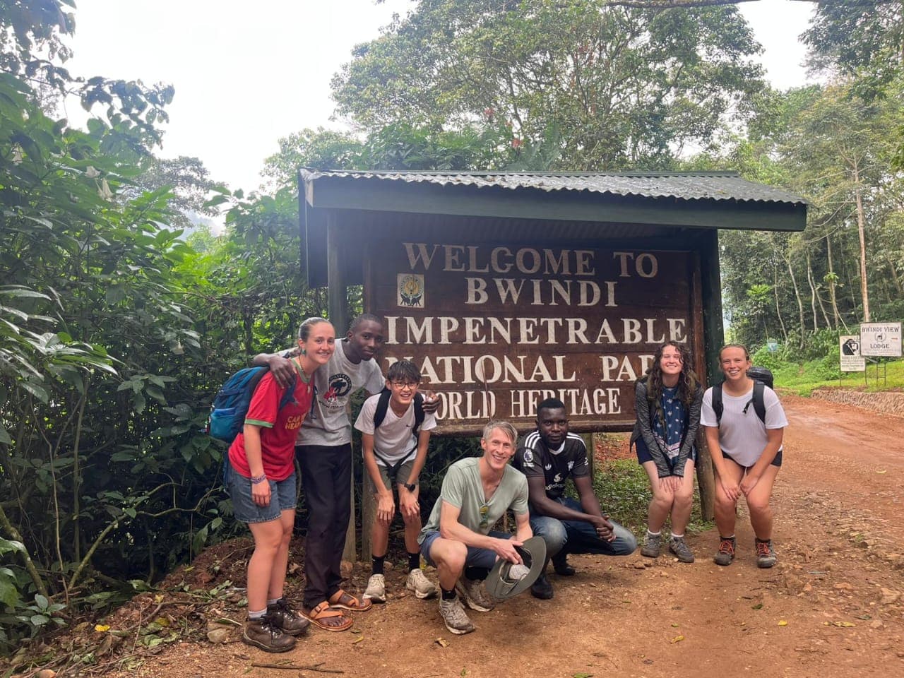 Team photograph at the official entrance sign for Bwindi Impenetrable National Park, UNESCO World Heritage Site.